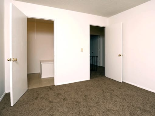 A room with a carpeted floor and two doors.