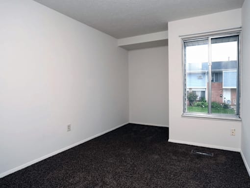 A room with a window and a carpeted floor.