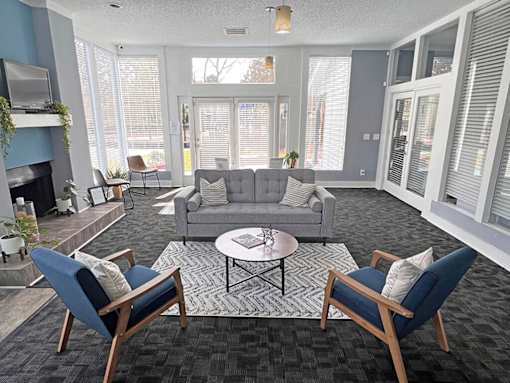 A living room with a grey couch, two chairs and a coffee table.