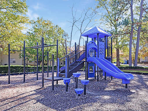 A playground with a blue slide and a black structure.