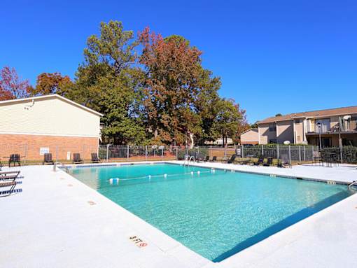 A large swimming pool surrounded by trees and buildings.