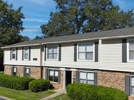 A row of townhouses with a green hedge in front.