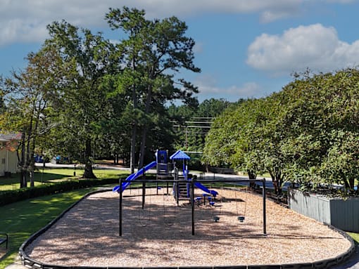 A playground with a blue slide and a brown surface.