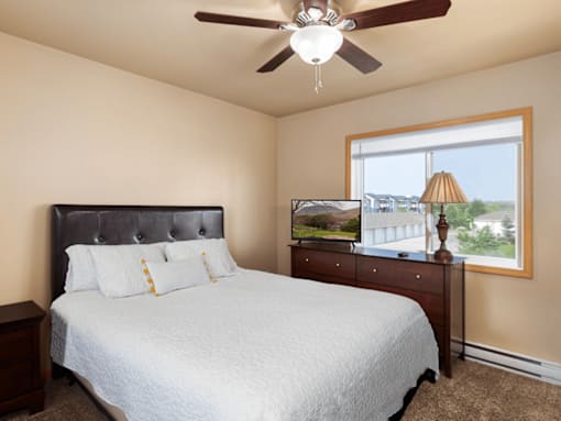 A bedroom with a bed, dresser, and window.