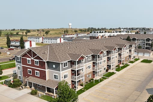 Apartment complex with a parking lot in front.