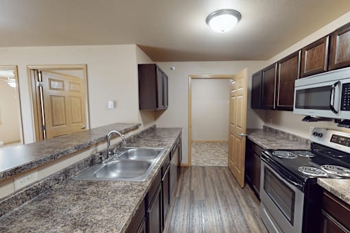 A kitchen with a stove, sink, and microwave.