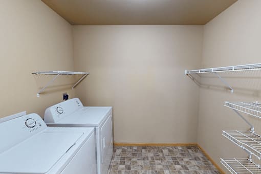 A laundry room with a washer and dryer and shelves.