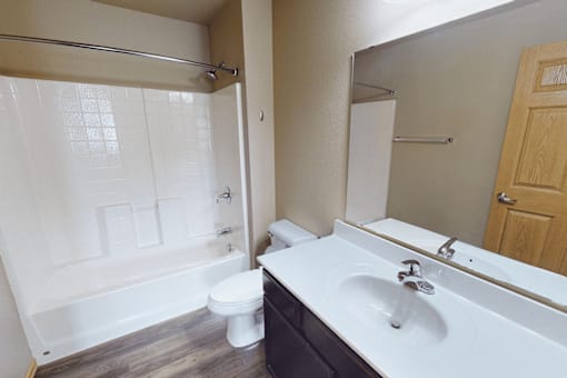 A white toilet sits in a bathroom next to a white sink.