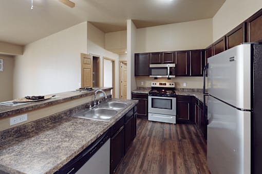 A kitchen with a white refrigerator, brown cabinets, and a wooden floor.