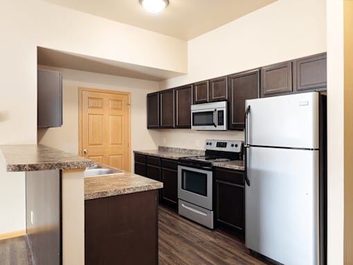 A kitchen with a white refrigerator, brown cabinets, and a granite countertop.