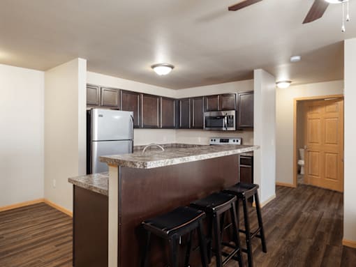 A kitchen with a refrigerator, microwave, and stove top oven.