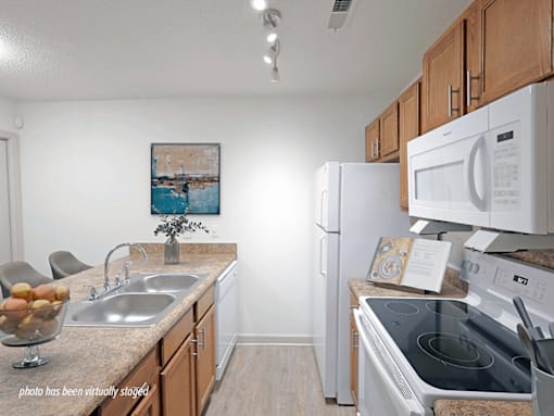A kitchen with a white fridge, white oven, and a painting on the wall.