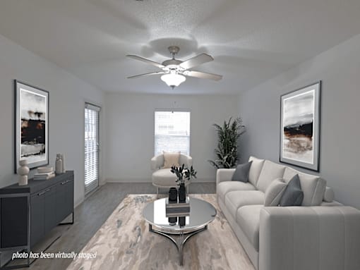 A living room with a grey couch, a coffee table, and a ceiling fan.