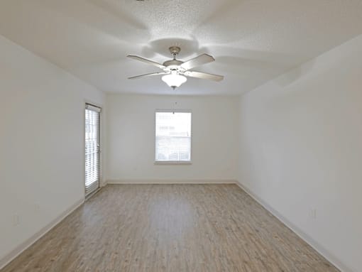 A room with a ceiling fan and wooden flooring.