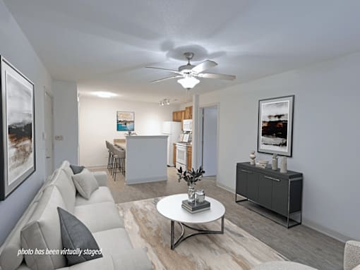 A living room with a grey couch, a white coffee table, and a ceiling fan.