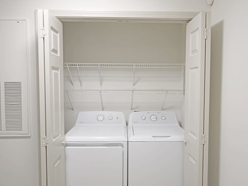 Two white front loading washing machines in a small laundry room.
