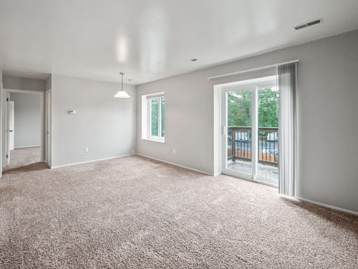 an empty living room with a sliding glass door to a balcony