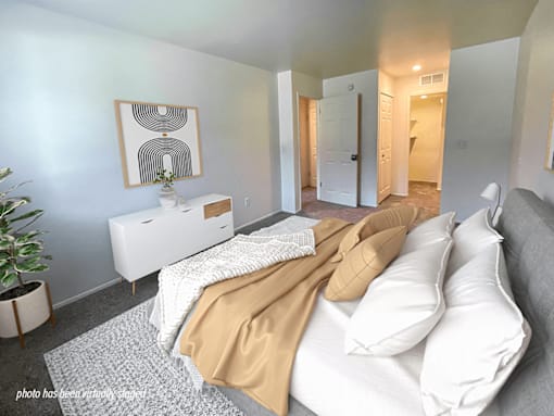 A bedroom with a bed, nightstand, and a painting on the wall.