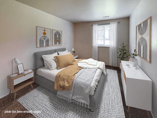A bedroom with a bed, nightstand, and a window with curtains.