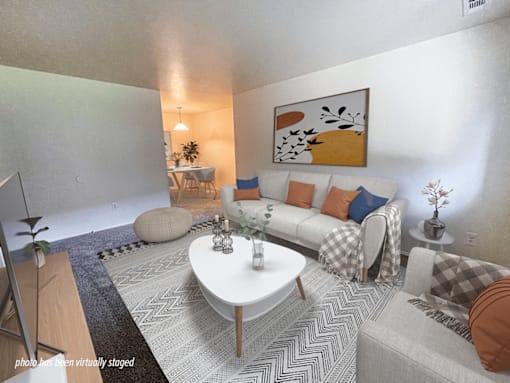 A living room with a white couch, a coffee table, and a painting on the wall.
