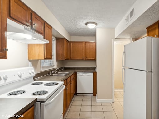 apartment kitchen with white appliances and wooden cabinets