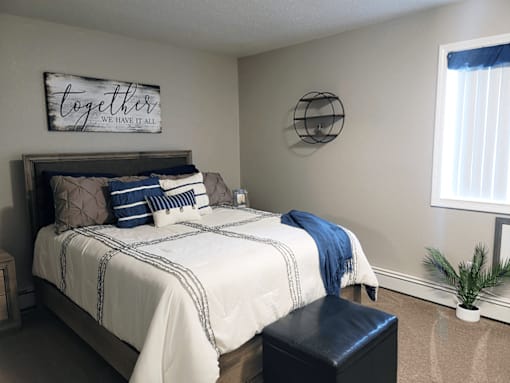 A bedroom with a bed, a bench, and a sign that says