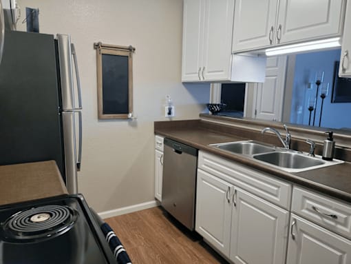A kitchen with white cabinets and a black refrigerator.