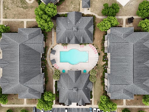 A bird's eye view of a neighborhood with a pool in the middle.
