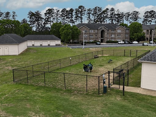 A tennis court is surrounded by a fence and a building is in the background.