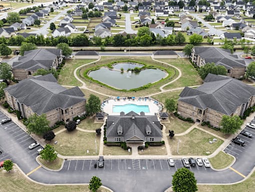 A bird's eye view of a residential area with a swimming pool and a pond.