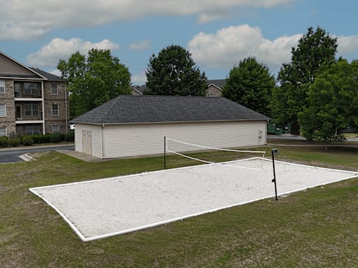 A white rink in the middle of a grassy area with a building in the background.