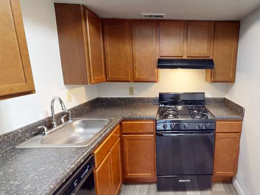 A kitchen with a black stove top oven and wooden cabinets.