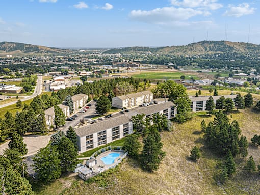 A large building with a pool in the foreground and a town in the background.