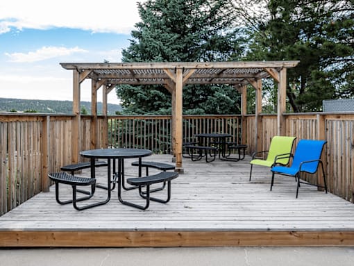 A wooden deck with a table and chairs under a pergola.