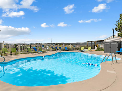 A large outdoor swimming pool with sun loungers and a clear blue sky.