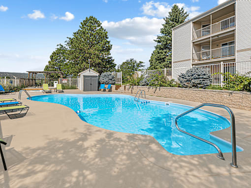 A small pool with a slide and a building in the background.