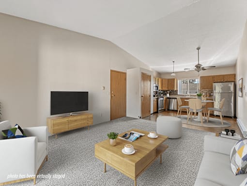 A living room with a television, a dining area, and a kitchen in the background.