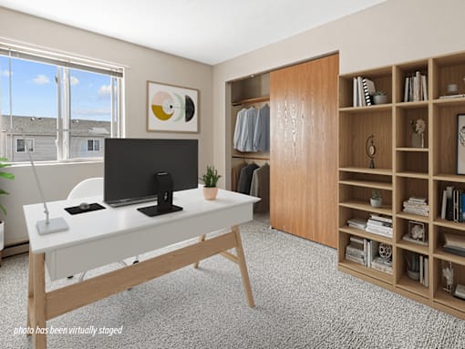 A modern home office with a desk, chair, and bookshelf.
