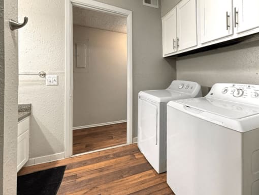a laundry room with a washer and dryer and white cabinets