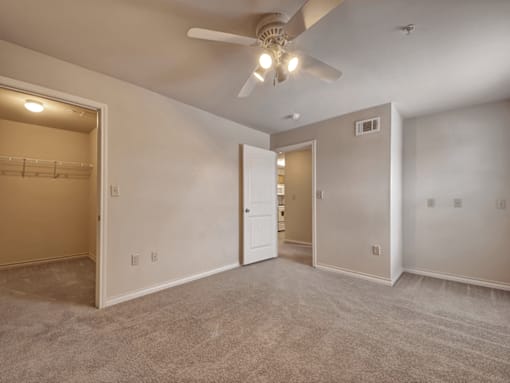 A spacious room with a ceiling fan and carpeted floor.