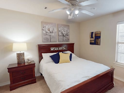 A bedroom with a bed, nightstand, and a ceiling fan.