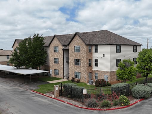 A large apartment complex with a parking lot in front.