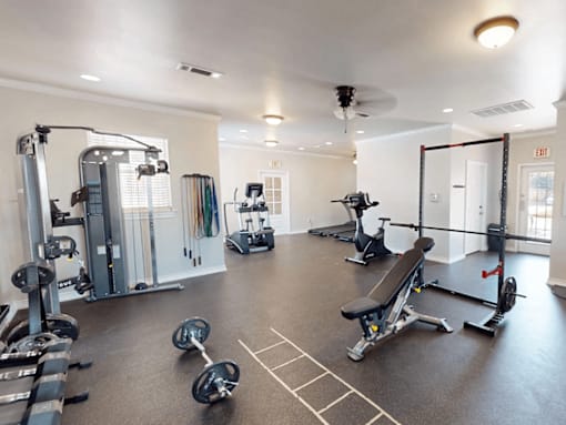 A spacious gym with a variety of equipment including a treadmill, elliptical machines, and weightlifting machines.