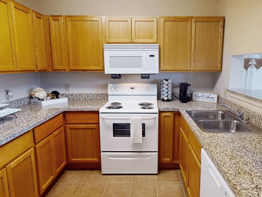 A kitchen with a white stove top oven and a white microwave above it.