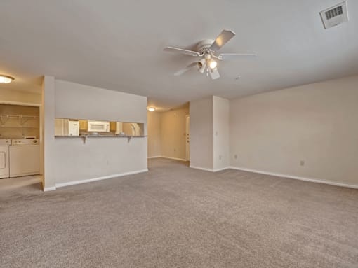 A spacious room with a ceiling fan and carpeted floor.