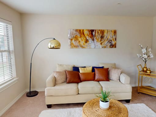 A living room with a white couch, a lamp, and a painting on the wall.