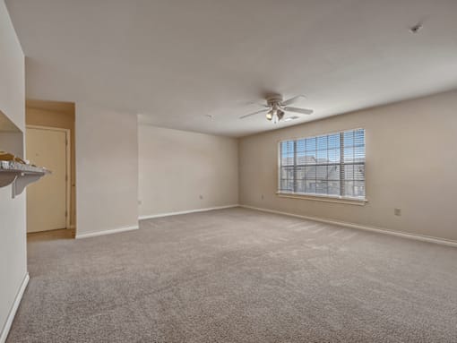 A spacious room with a ceiling fan and a window.