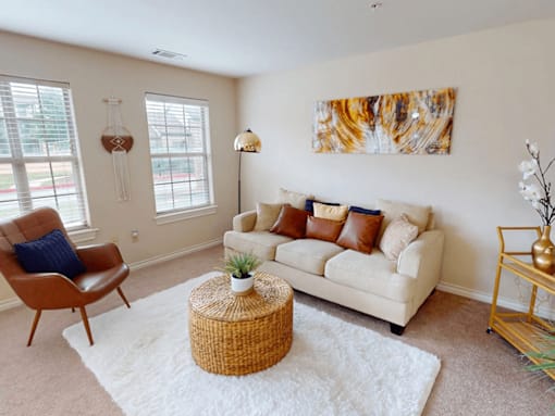 A living room with a white couch, a brown chair, and a wicker table.