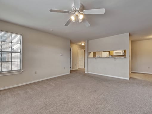 A spacious room with a ceiling fan and carpeted floor.