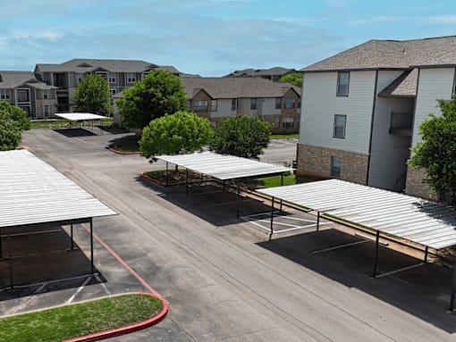 A parking lot with a few cars and a building in the background.
